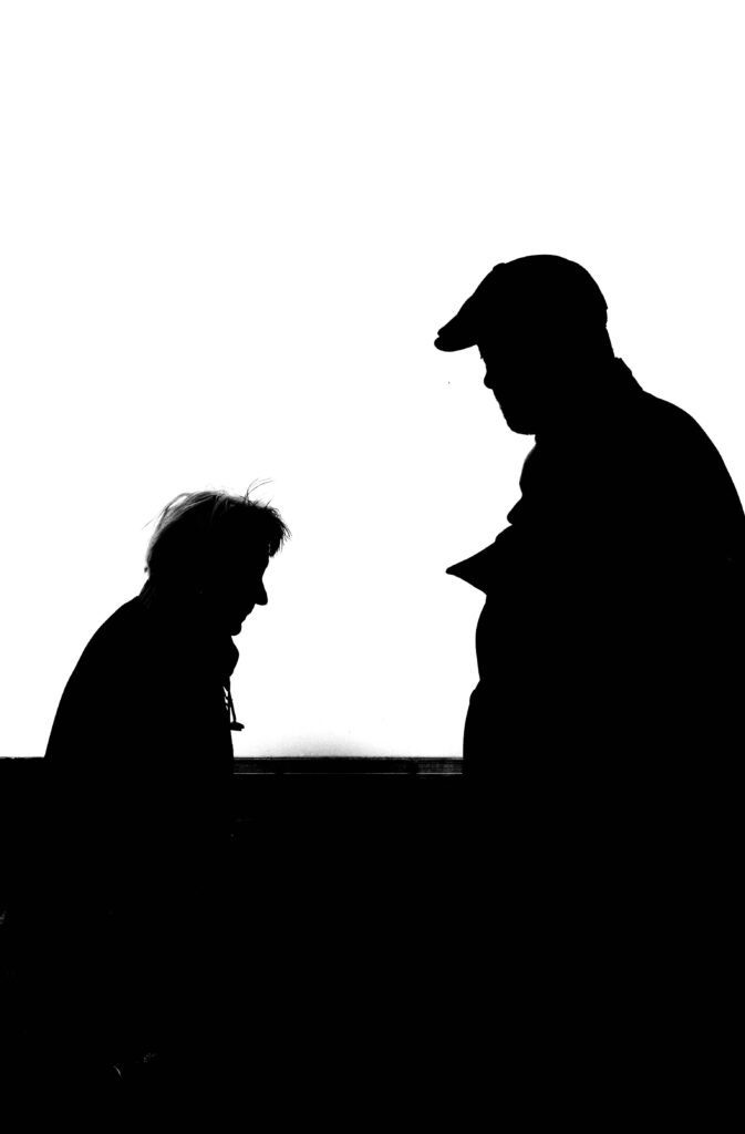 Discuss Hard Truths Without Losing Your Humanity High contrast silhouette photo capturing two adults conversing against a white background.